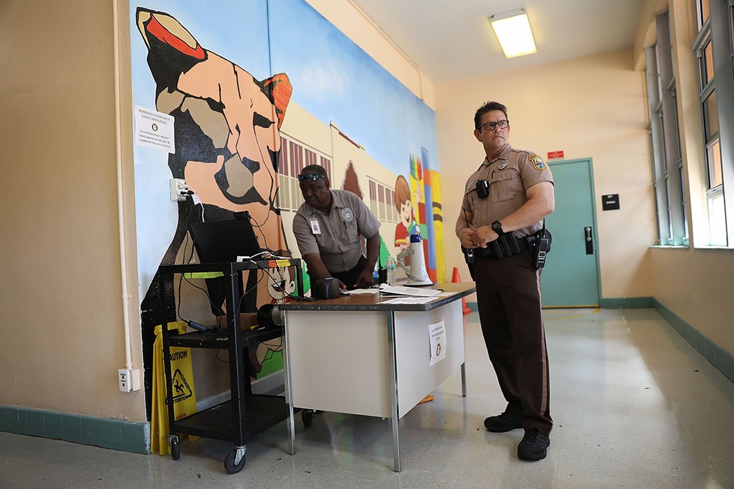 The head of school security, and a Miami-Dade Police officer stand at the front entrance to the Kenwood K-8 Center on August 24, 2018 in Miami, Florida.