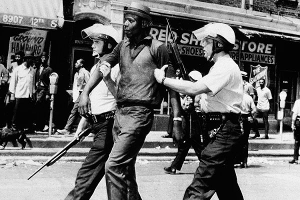 Two police officers in full riot gear arrest a Black man during a breakout of rioting and looting on the West side of Detroit, Michigan, July 23, 1967.