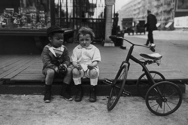 Two boys share candy on a New York street, circa 1925