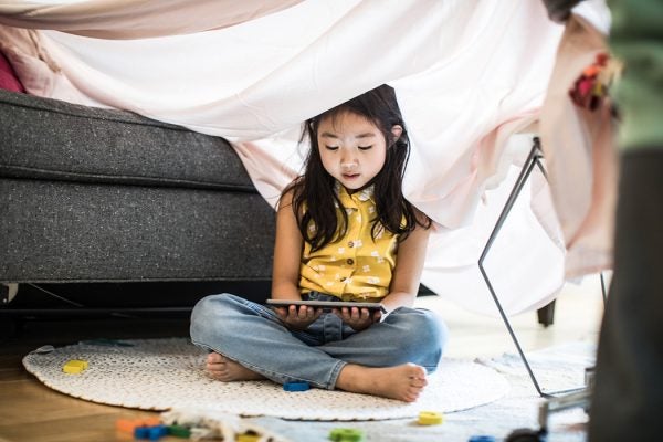 Young girl using tablet in homemade fort at home