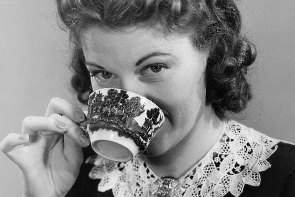:A woman drinking from a cup of tea