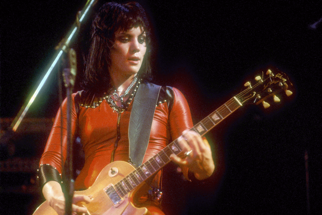 A mother plays the guitar while her two daughters sing / Guitarist Joan Jett of the rock band "The Runaways" performs on stage in Los Angeles in August, 1977
