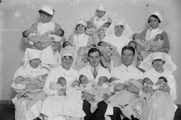 Babies from the City Maternity Hospital being held by the nurses and doctors who had delivered them.