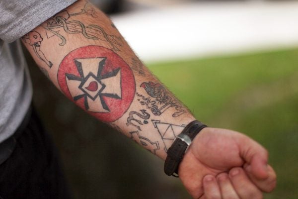 A man displays a Ku Klux Klan cross tattooed onto his arm