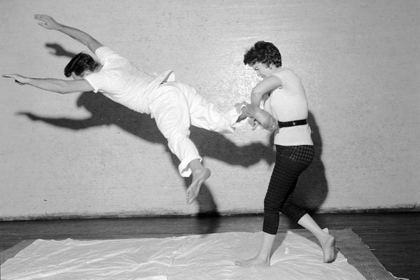 At a self-defence demonstration a woman uses a judo heel and leg turnover against a kicking attacker.