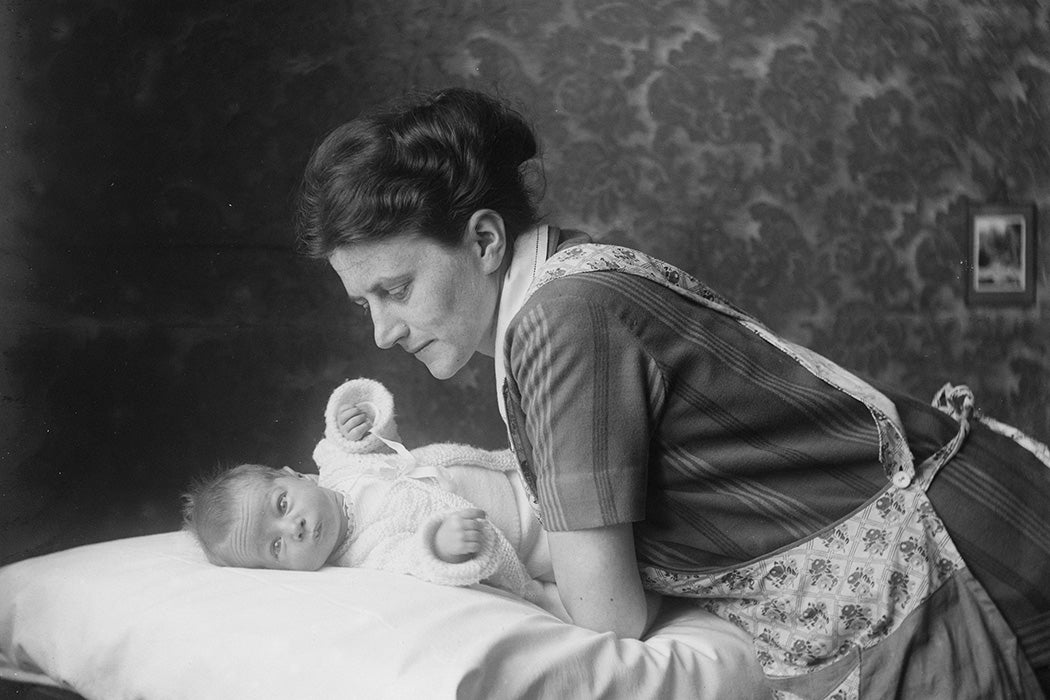 Black and white photo of caring mother leaning over her baby