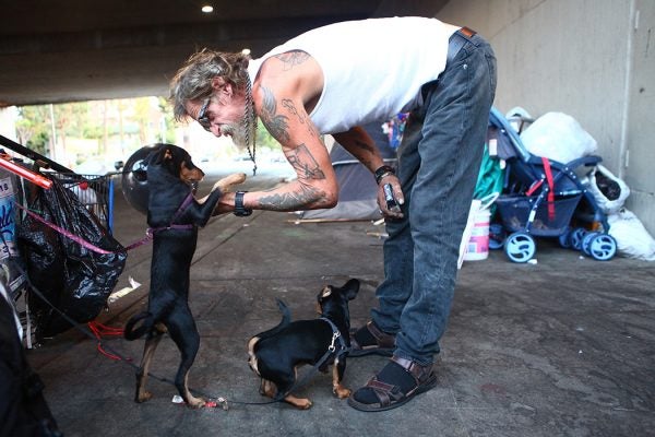 Antonio DeSilva, who is currently homeless, plays with his dogs outside his tent on September 09, 2019 in Los Angeles, California