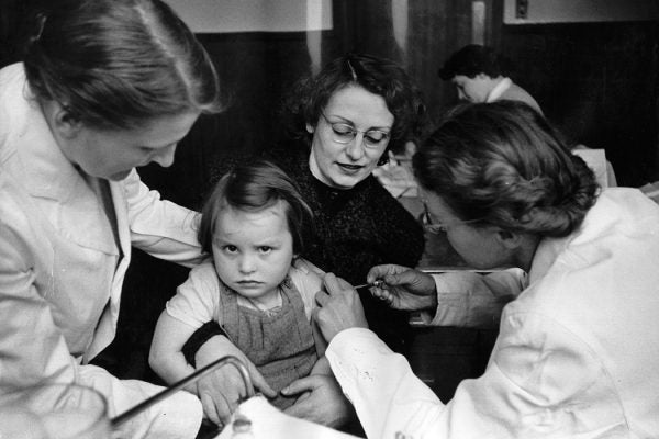 A rather reluctant-looking girl is given an injection of vaccine