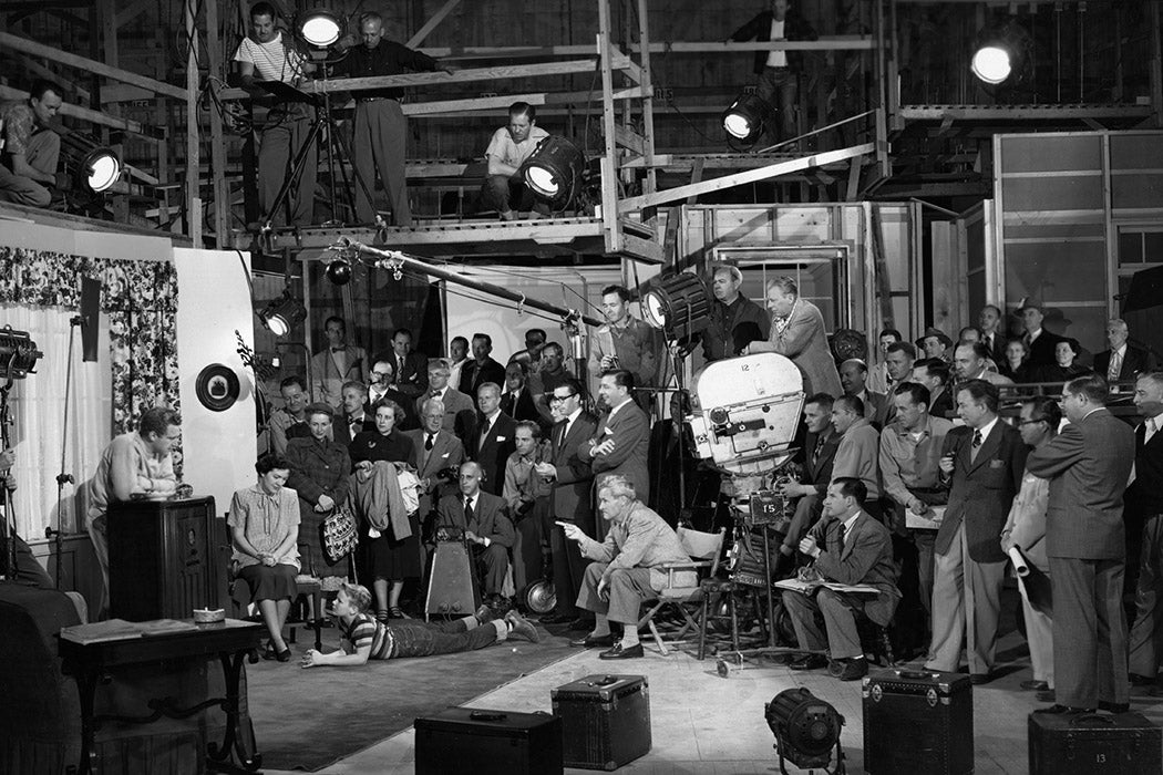 The cast and crew of a 1950's film at work on a sound stage