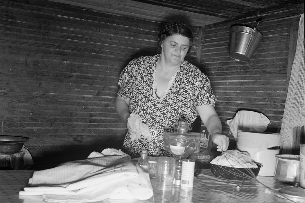 Tobacco sharecropper's wife cleaning up table after washing breakfast dishes. Person County, North Carolina, 1939, by Dorothea Lange