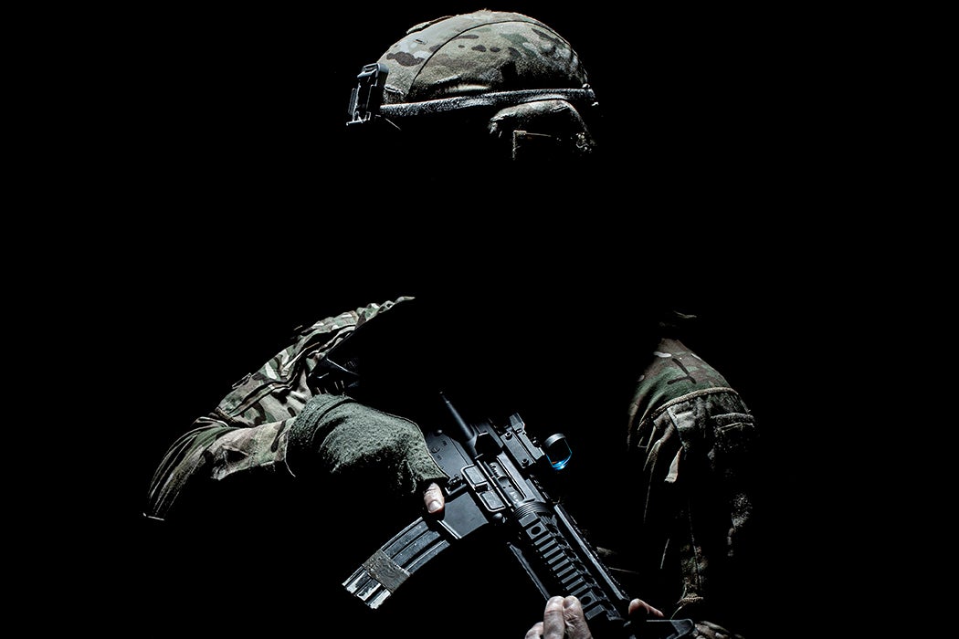A soldier in shadow, holding a gun
