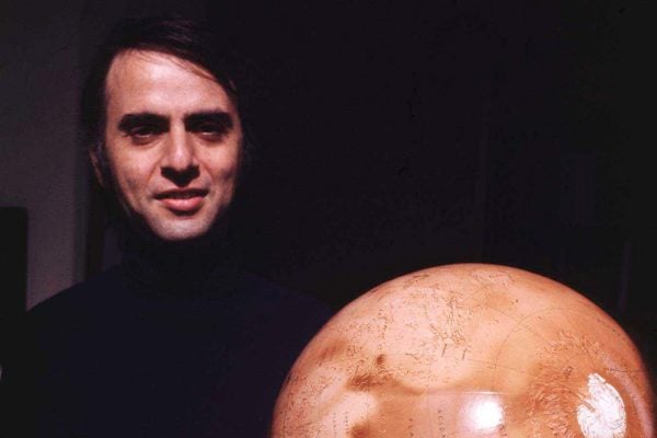 Carl Sagan holding a globe model of the planet Mars, 1970s.