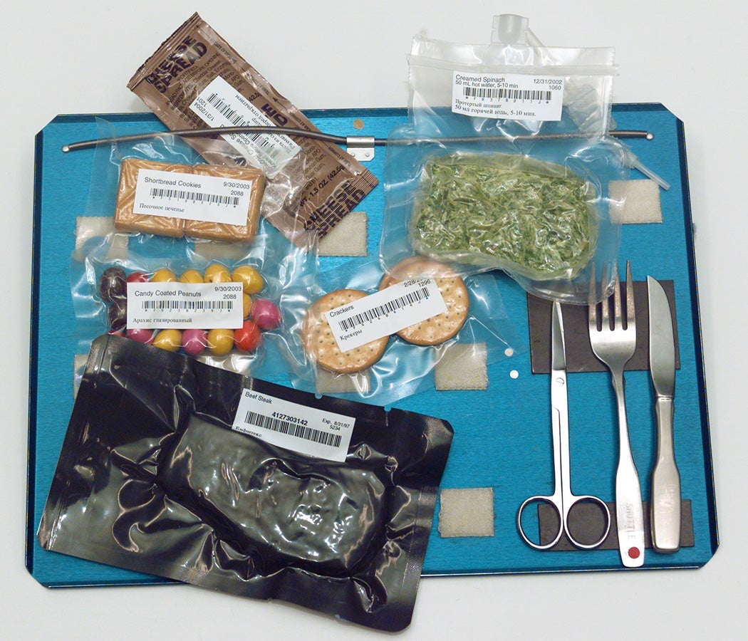 Bags of International Space Station food and utensils on a tray