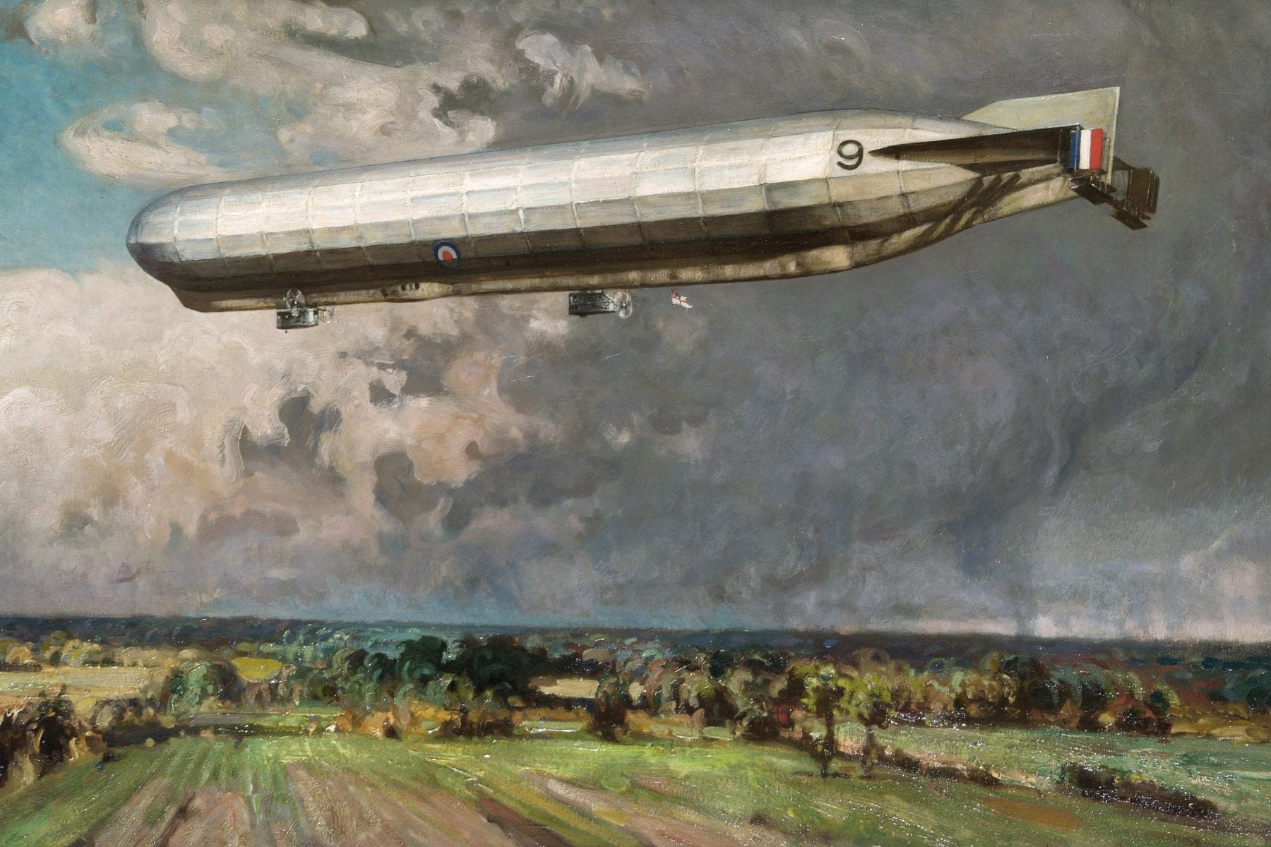 A British airship in flight above the British countryside set against a cloudy sky, 1918