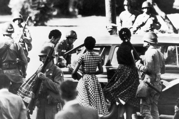 Black students are provided with a military escort when entering and leaving Little Rock Central High School, Arkansas, following the school's desegregation, 1957