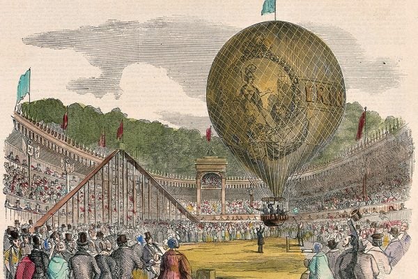 Large crowds of people have gathered to watch a hot-air balloon