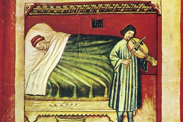 A medieval illustration of a person in bed
