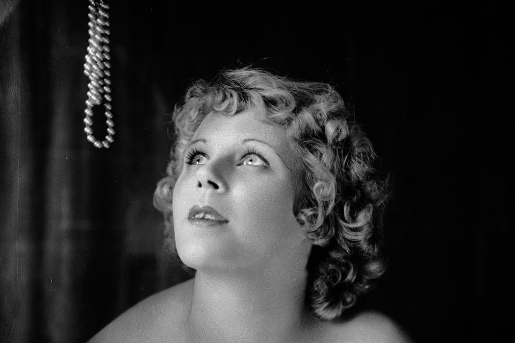 Actress Bobby Bradshaw is tempted by a pearl necklace, 1925 Getty