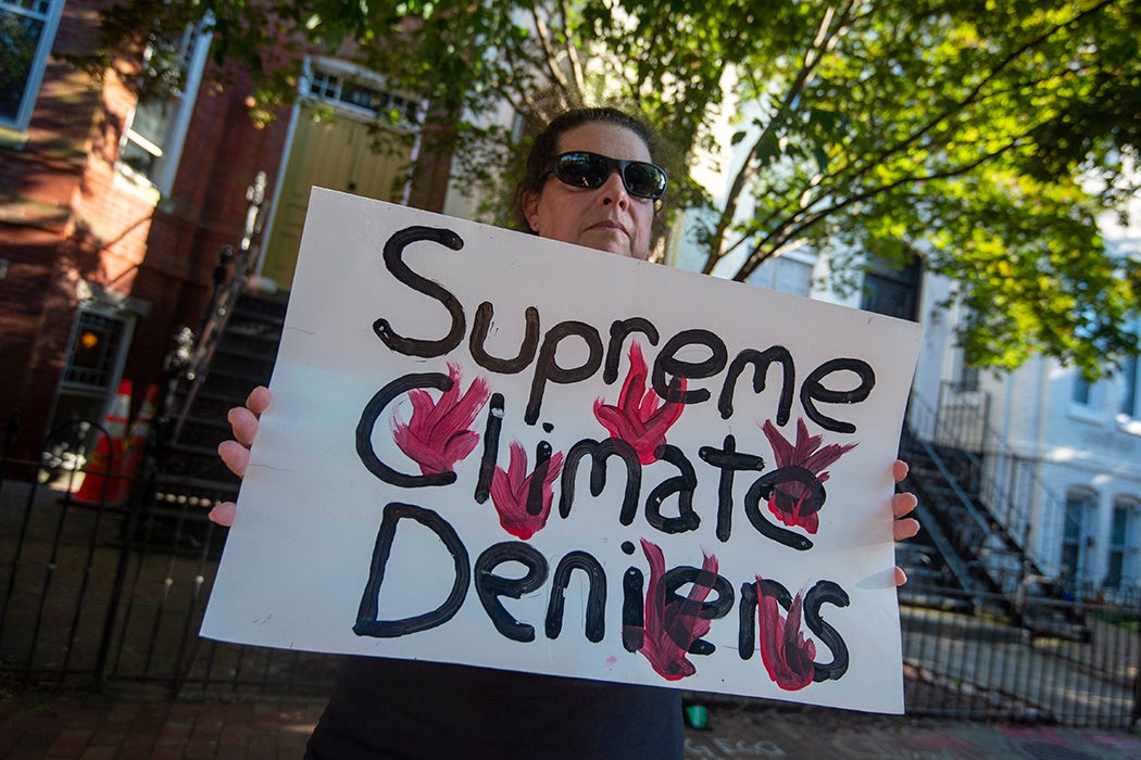 A climate change activist stands outside the home of Sen. Ben Sasse (R-NE) on June 30, 2022 in Washington, DC. Activist groups are holding a "Tour of Shame", or march to the homes of senators they consider most responsible for a reduction in climate change regulations.