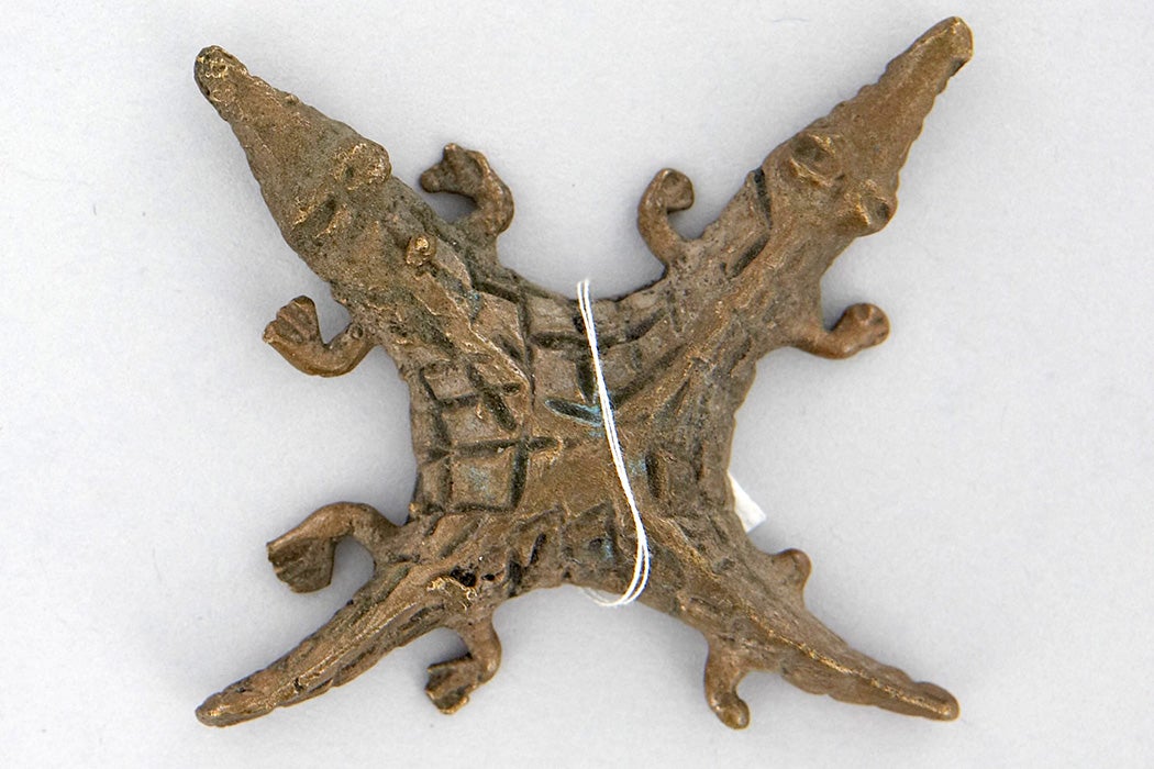 Split crocodile brass weight in the shape of a star with four points. Two of the points are the crocodiles' tails and two of points are the crocodiles' heads.