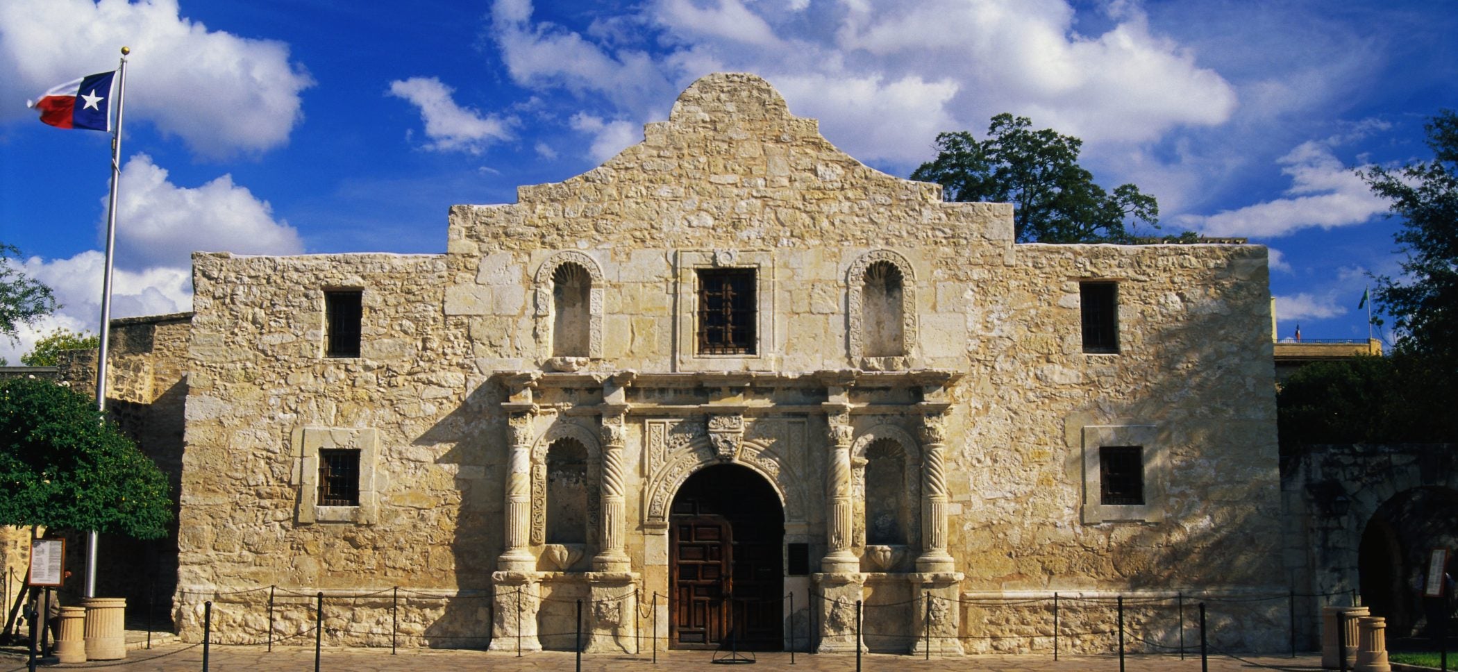 The Alamo by day with the Texas flag waving