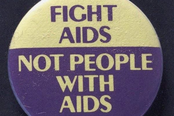A yellow and purple button with "Fight AIDS, Not People with AIDS" in yellow and purple font.