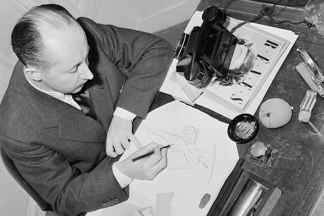 Photograph: French fashion designer Christian Dior sketches a dress at his salon in Paris, France, February 1948

Source: Getty