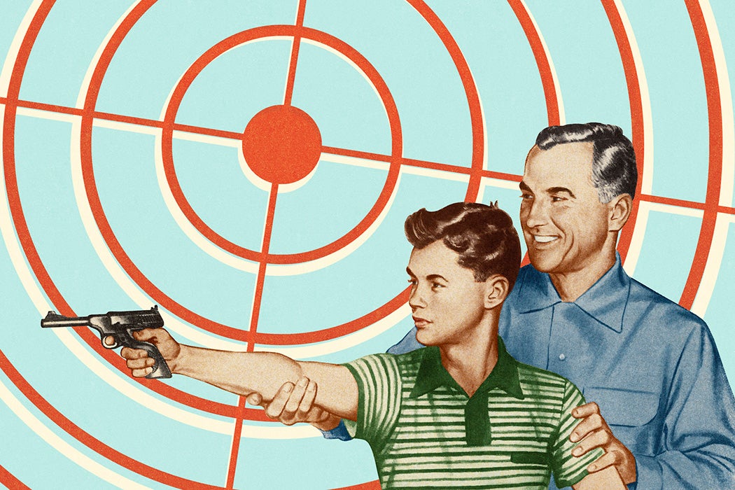 A child being taught how to shoot a gun by his father
