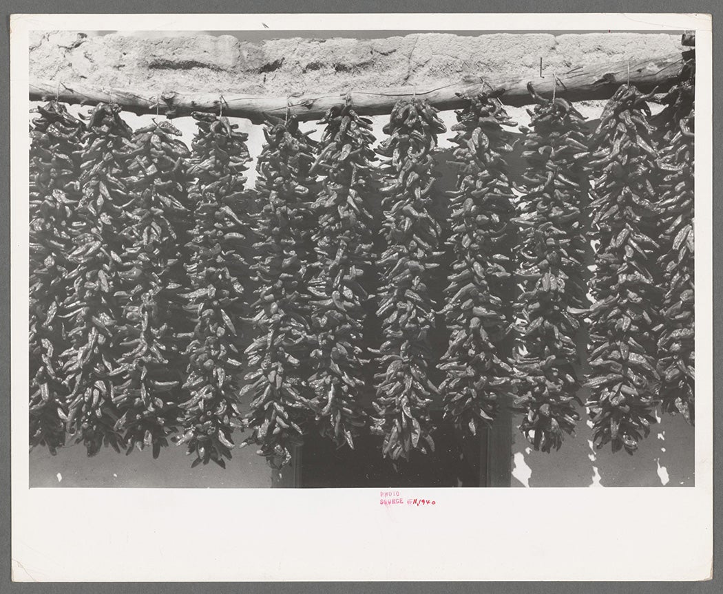 Chili peppers hanging from adobe house top while drying