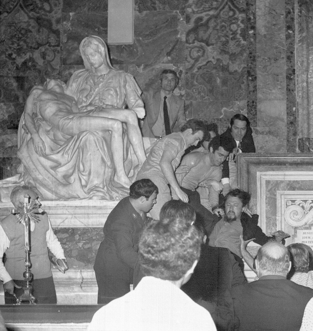 Bystanders drag Laszlo Toth, (right) away from Michelangelo's statue of the Pieta in St. Peter's after he smashed it with a hammer May 21, 1972