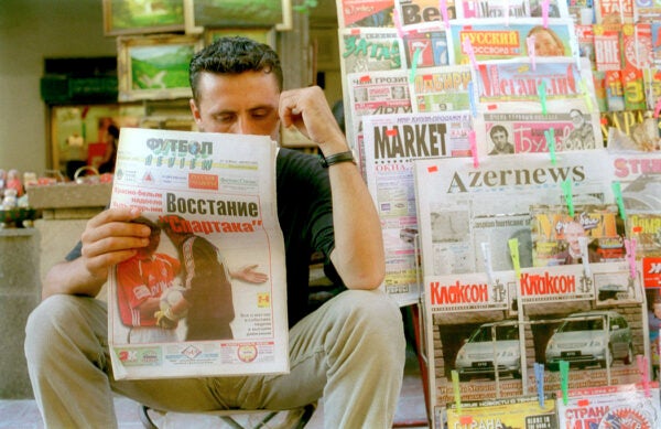 A newspaper vendor reads an edition of the sports colum of a newspaper printed in Russian July 31, 2001 in downtown Baku, Azerbaijan. In accordance with a decree issued by President Heydar Aliyev last June, Azerbaijan had to change all its Azeric writing, including books, newspapers, and street signs from the old Soviet-era Cyrillic to Latin script on August 1.