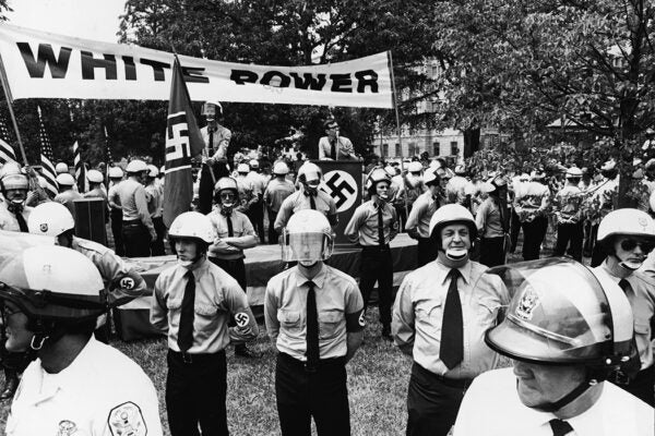 An unidentified neo-Nazi gives a speech from a podium under a 'White Power' banner in Lafayette Park surrounded by his followers who are, in turn, surrounded by police watching for trouble, Washington DC, July 3, 1973.