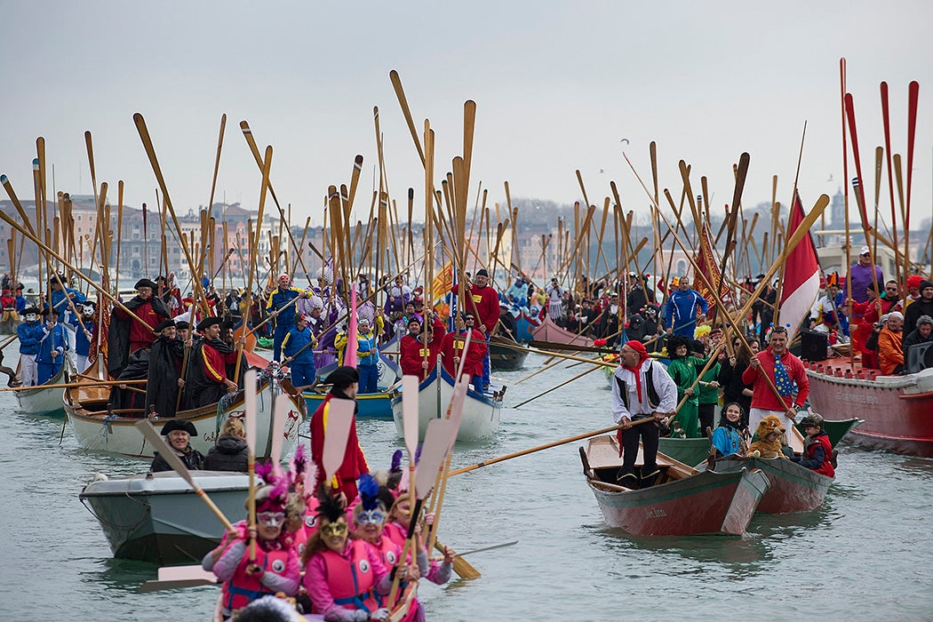 Rowers lift their oars in sign of salute ahead of the traditional regatta on the Grand Canal which officially opens the Venice Carnival on February 16, 2014 in Venice, Italy.