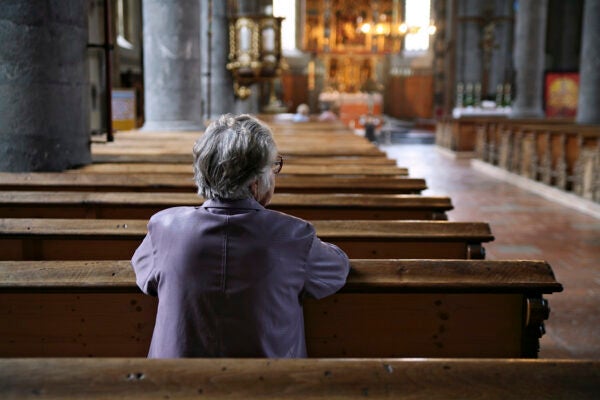 Older woman praying in an almost empty church.