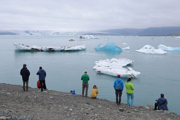 Tourists look at icebergs that have broken off of receding Breidamerkurjokull glacier, which looms behind, at Jokulsarlon lake on August 15, 2021 near Hof, Iceland.