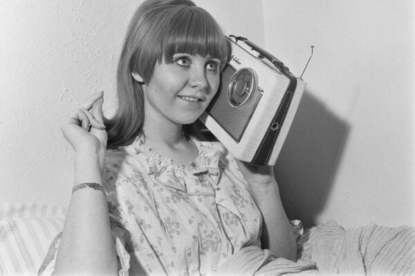Scottish singer and actress Lulu listens to a small portable Rhapsody DeLuxe radio