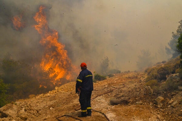 A firefighter runs so not to be surrounded by fire as he tries to extinguish a wildfire burning near the village Vlyhada near Athens on July 19, 2023 in Athens, Greece.