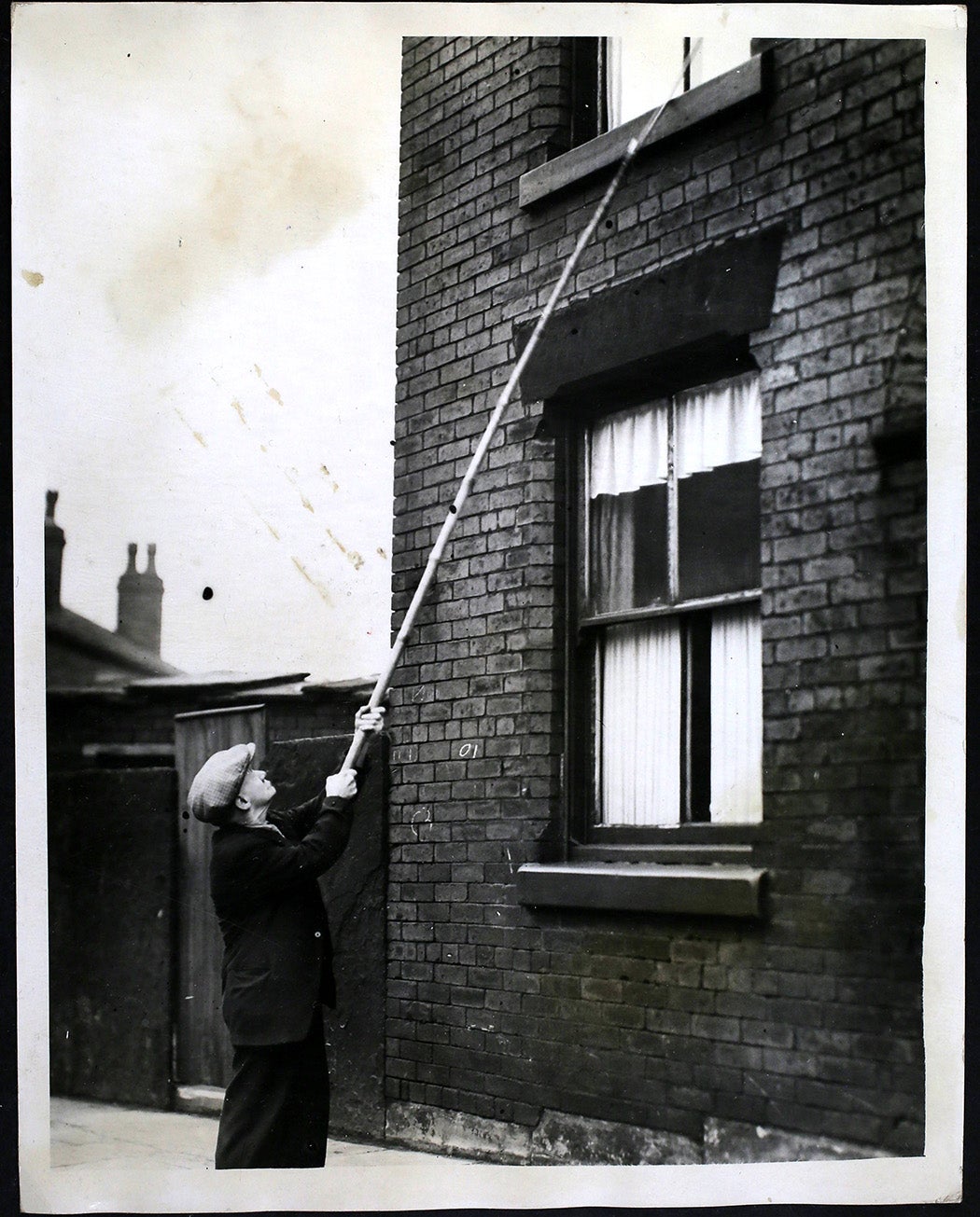 Alarm Clock Rouses Oldest Knocker -Up, The introduction of cheap alarm clocks threatened Mr William Crompton of Bolton. He is the oldest of the knocker-ups who wake factory workers every morning. Alarm clocks put most of the knocker-ups out of business but Mr Crompton, now seventy two, survived the challenge, and still carries on after fifty three years. Strangely enough Mr Crompton is himself awakened by an alarm clock. He rises at 3:45 am and charges from fourpence to sixpence a week, according to time he calls his customers. - Mr Crompton, the oldest knocker-up, at work in Bolton, Bolton. (Photo by Hulton Archive/Getty Images)