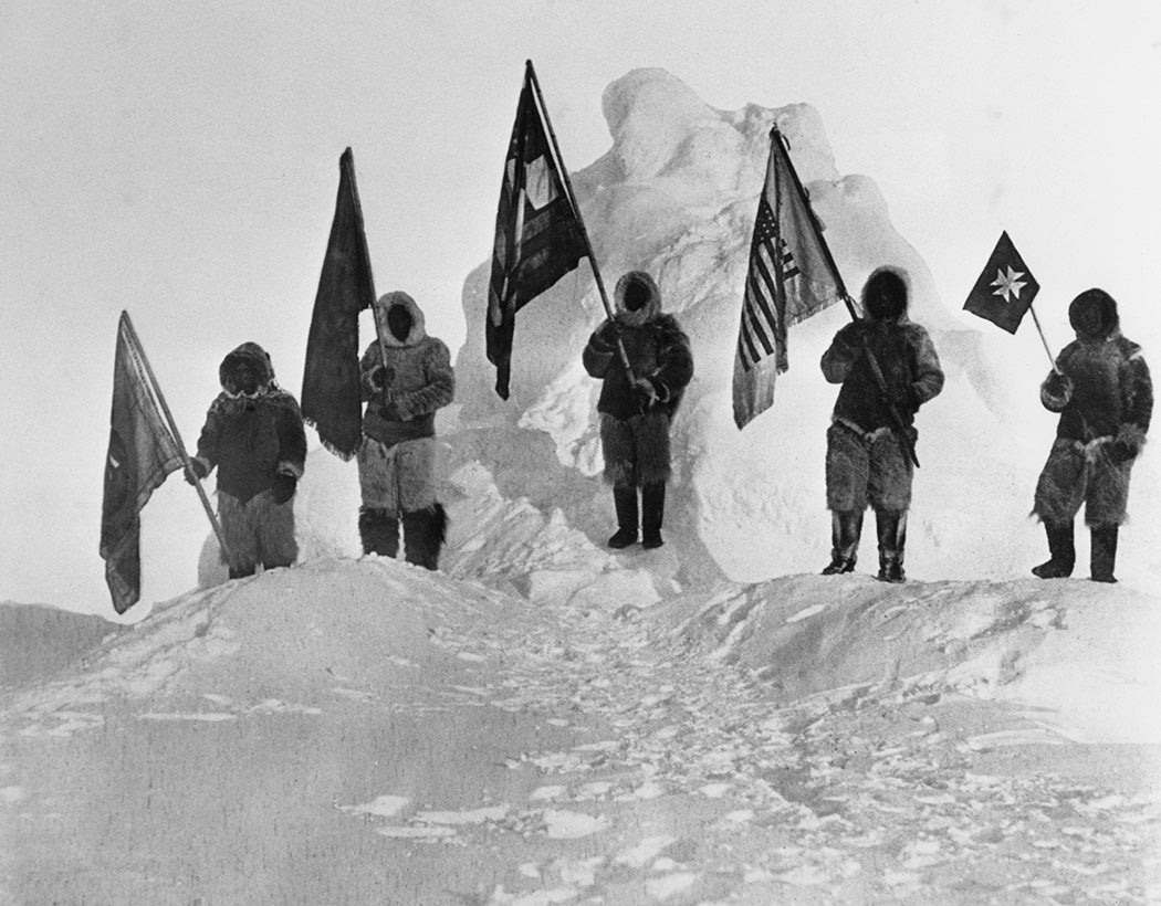 Robert Peary's fellow discoverers dressed in furs and holding flags at the North Pole. L-R: Ooqueah holds the Navy League flag, Ootah holds the Delta Kappa Epsilon fraternity flag, Matthew Henson holds the US flag, Egingwah holds the DAR peace flag, and Seegloo holds the Red Cross flag. Getty