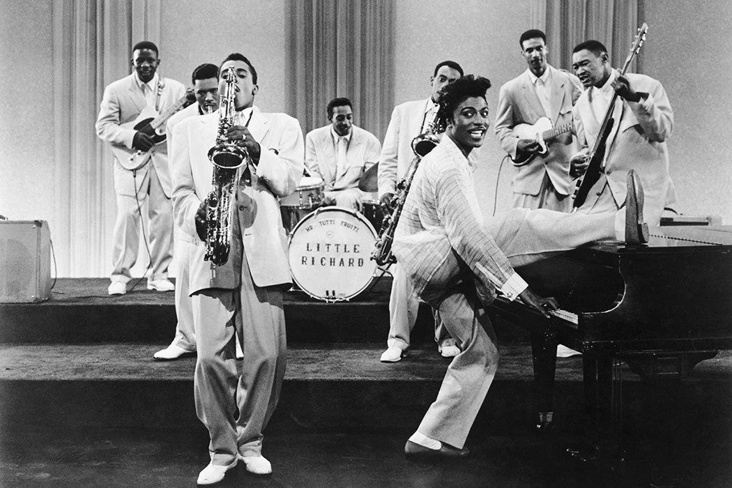 Musician Little Richard performs onstage with his band as his saxophone player Grady Gaines stands on the piano in circa 1957 in scene from the movie 'Mister Rock And Roll.'