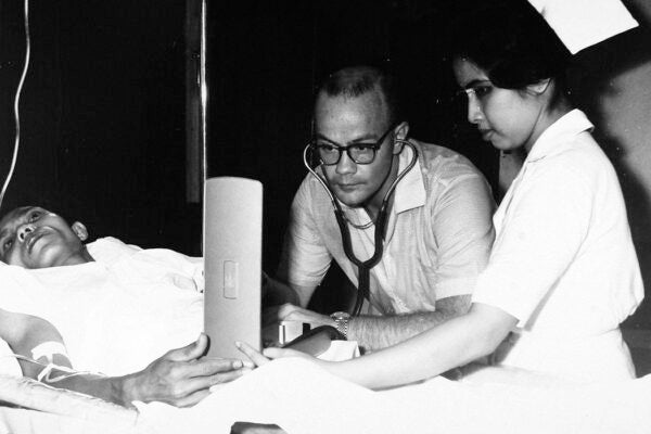 A doctor in the Philippines checks a patient’s blood pressure assisted by Filipina Nurse C.P. De Batan, 1963