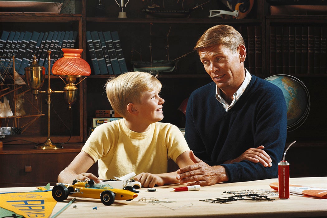 Father talking to son at a workbench in the home