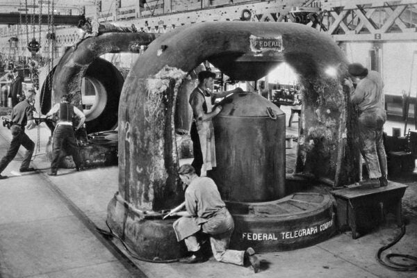 Workmen at Federal Telegraph smoothing two castings for 80-ton magnets.