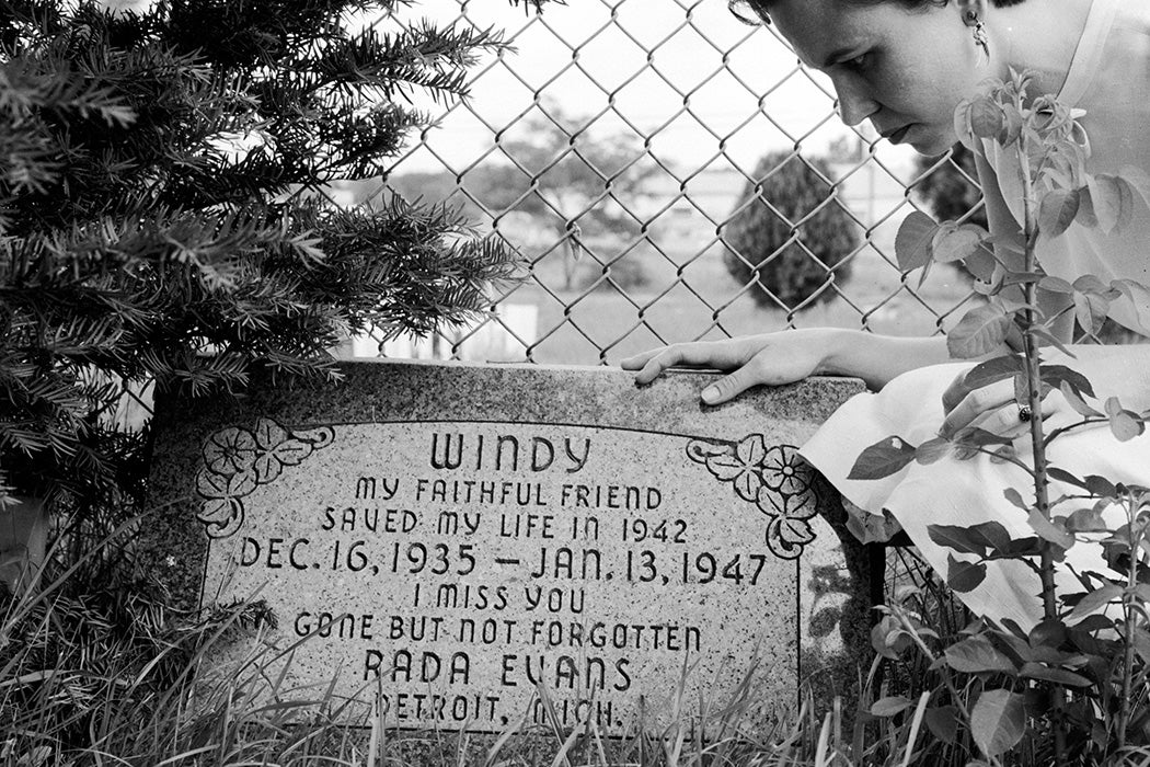 A woman kneels at the headstone in the Detroit Canine Cemetery in Michigan