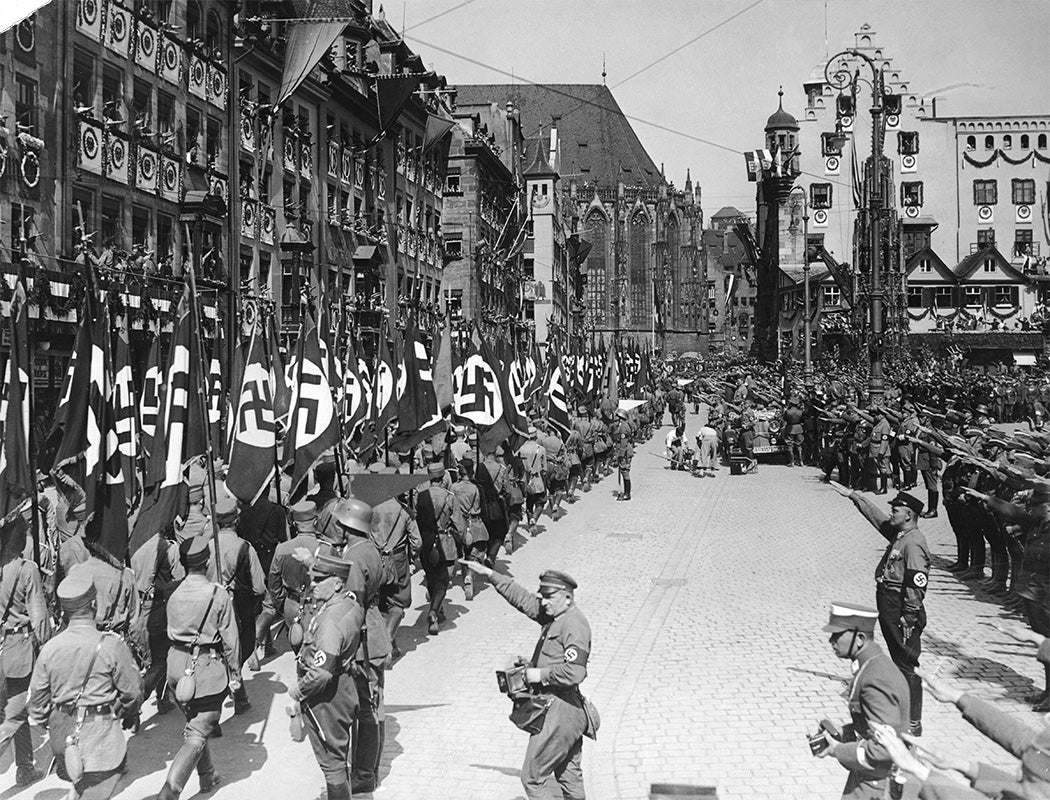 Nazi storm troops march past German Nazi leader Adolf Hitler (standing in car, right) at a parade in Nuremberg, Germany, during the Party Congress, September 1934