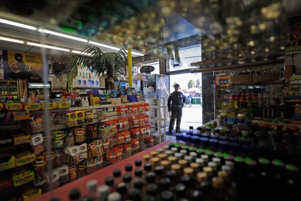 A security officer keeps watch at the entrance of Tom Liquor store at the intersection of Florence and Normandy in South Los Angeles, 201