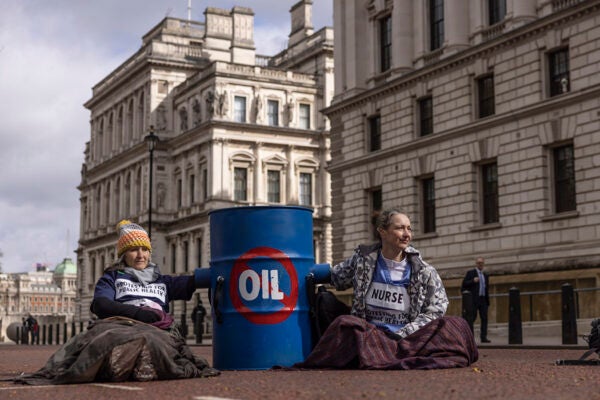 Extinction Rebellion (XR) protesters glue themselves to barrels outside the Treasury on April 07, 2022 in London, England.