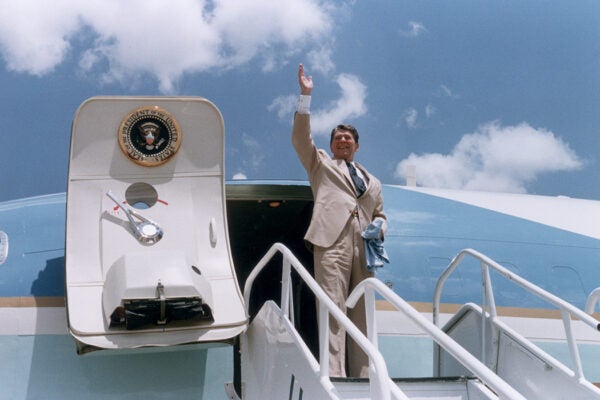 US President Ronald Reagan waves as he stands at the top of a stairway, preparing to board Air Force One, Dothan, Alabama, 1986