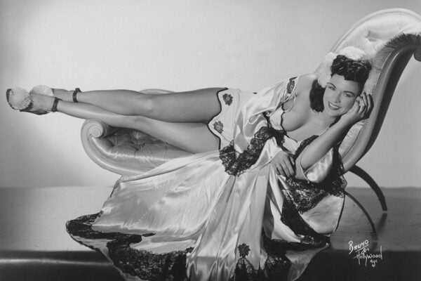 Burlesque dancer Mary Mack reclining on a chaise longue, circa 1950.