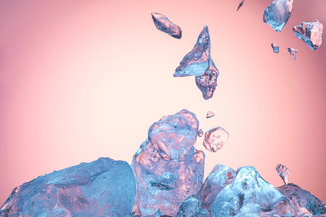 Blue ice block exploding into shards on pink background